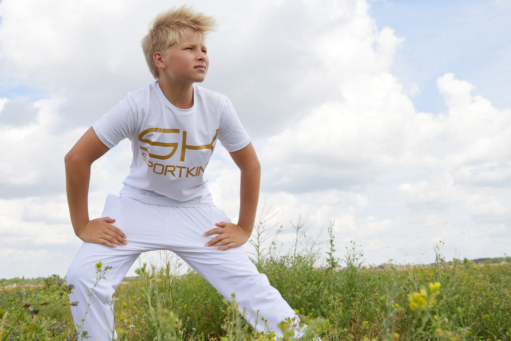 Junge mit weißer Sportkind Kleidung bestehend aus T-Shirt und Jogginghose